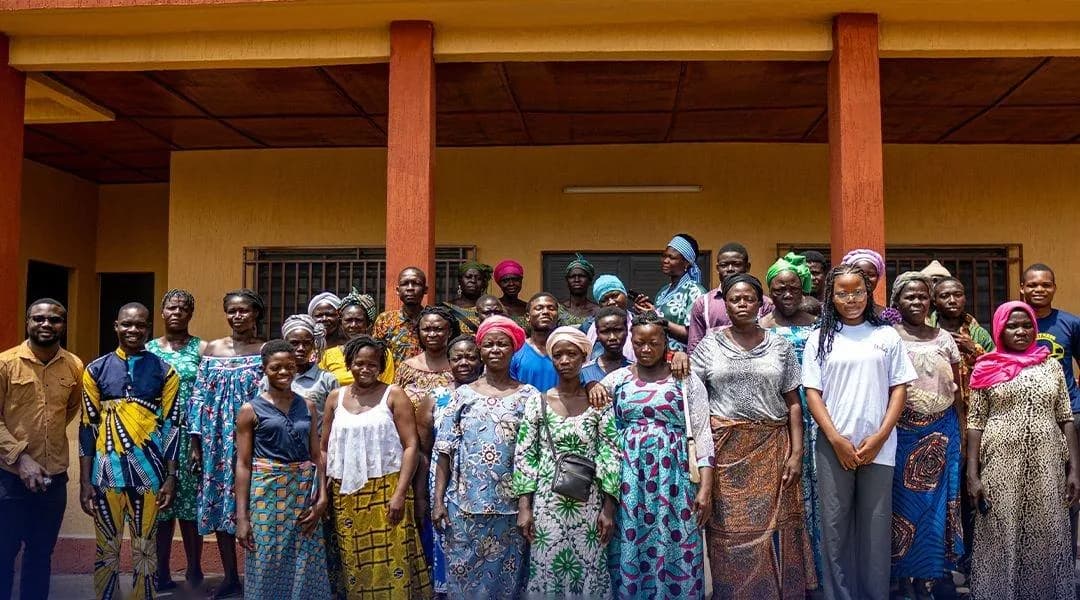 Several dozen women gathered in front of a community building for a voice data collection session